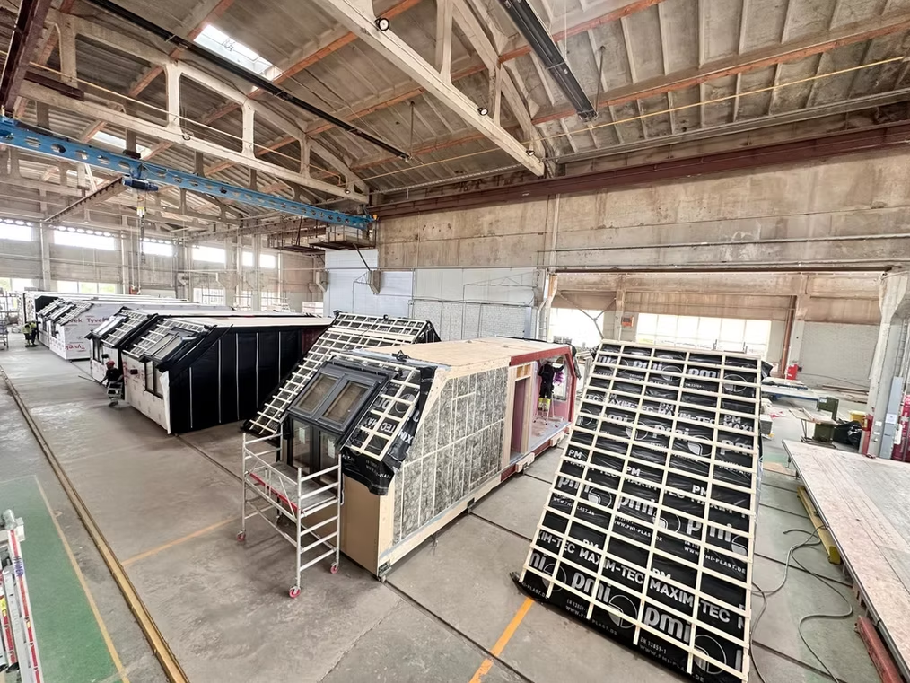 Production line of rooftop home modules being glazed and insulated inside a manufacturing hall